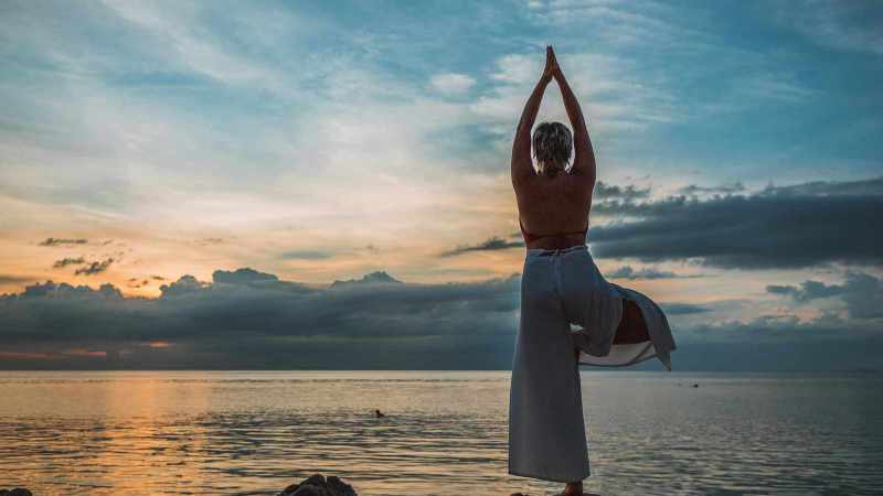 Frau macht Yoga am See